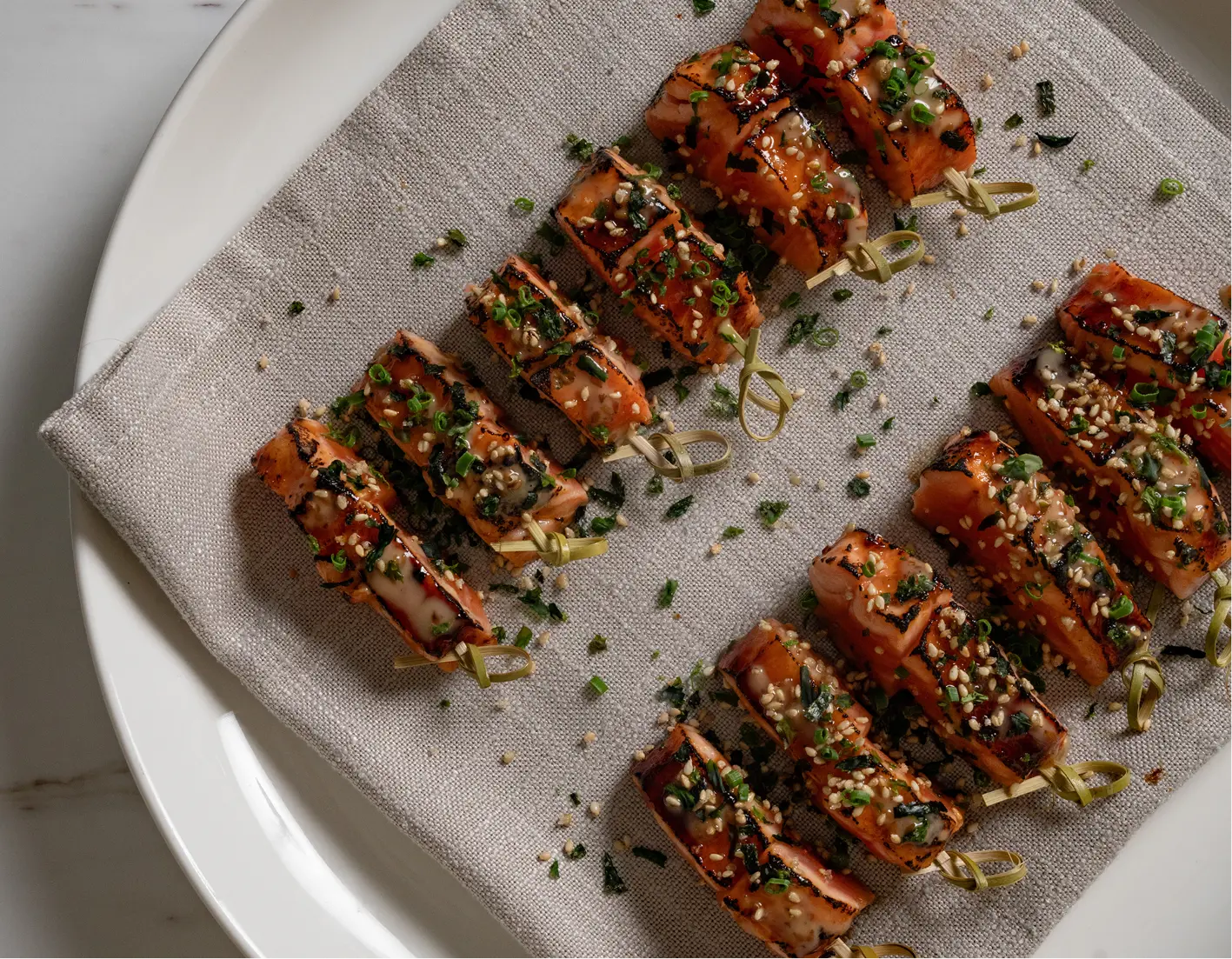 Glazed salmon bites with sesame and spring onion plated for an elegant 60th birthday dinner