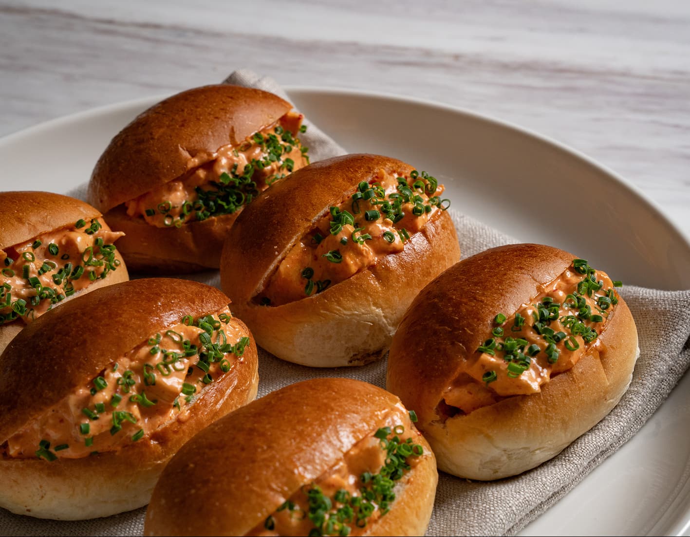 Brioche rolls filled with a chive topped seafood mix for a cocktail style business lunch