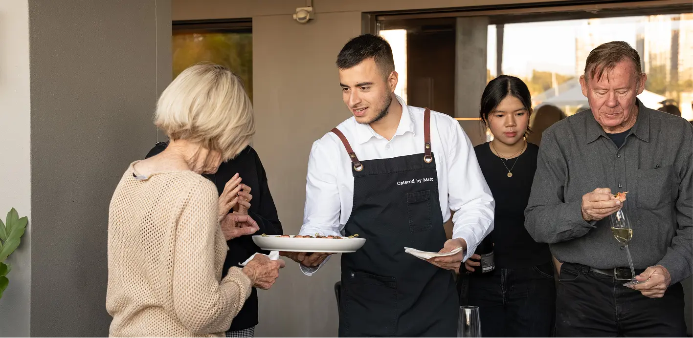Waiter offering a canapé selection to guests at a large Sydney gathering