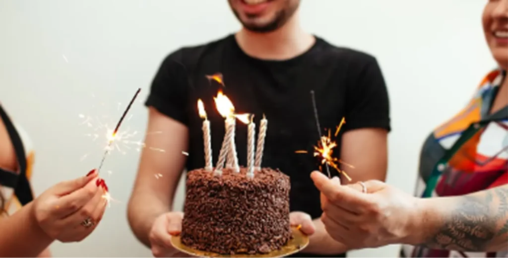 Group celebrating a 40th birthday with cake and sparklers