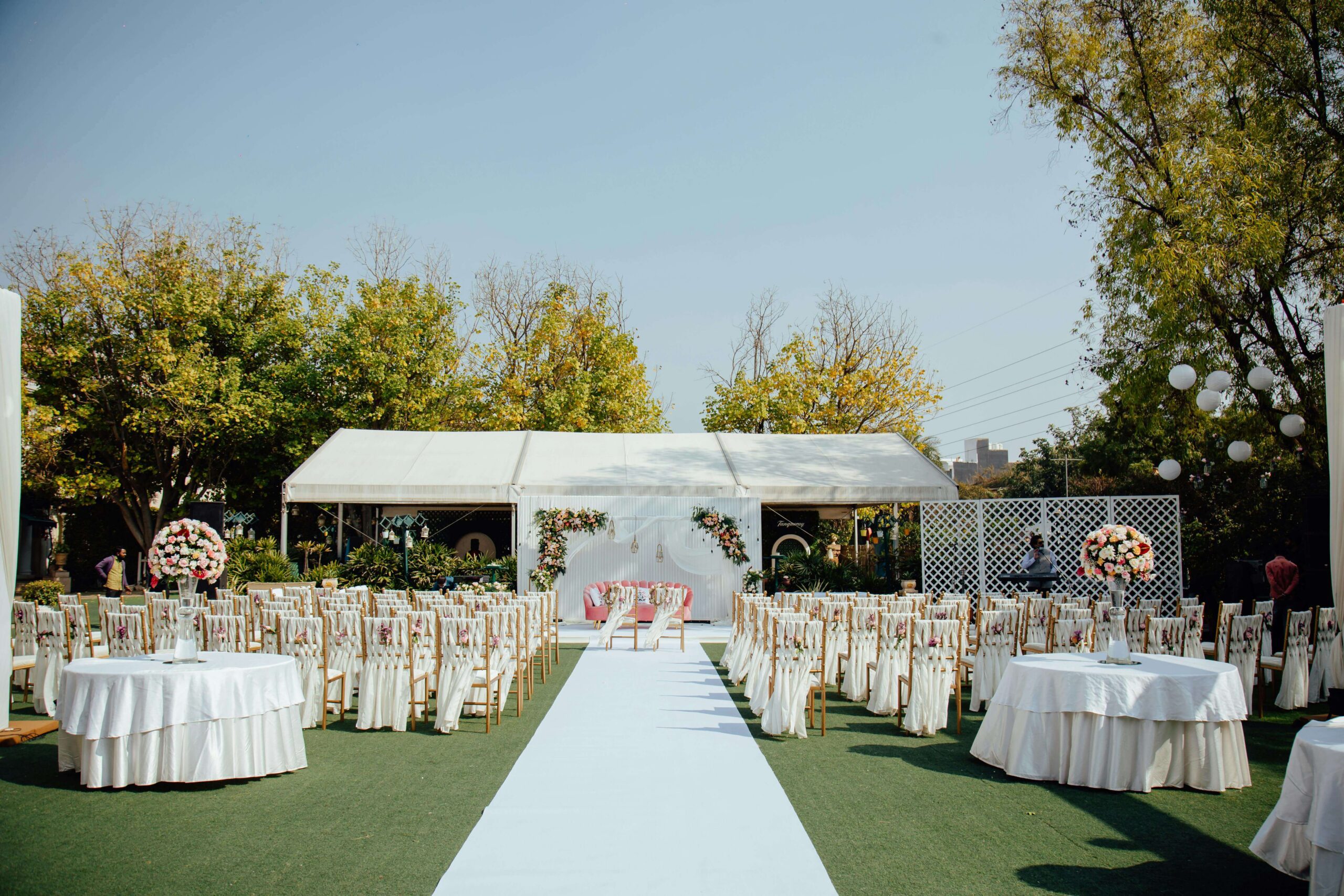 Garden wedding setup for 80 guests with tables, chairs and floral décor