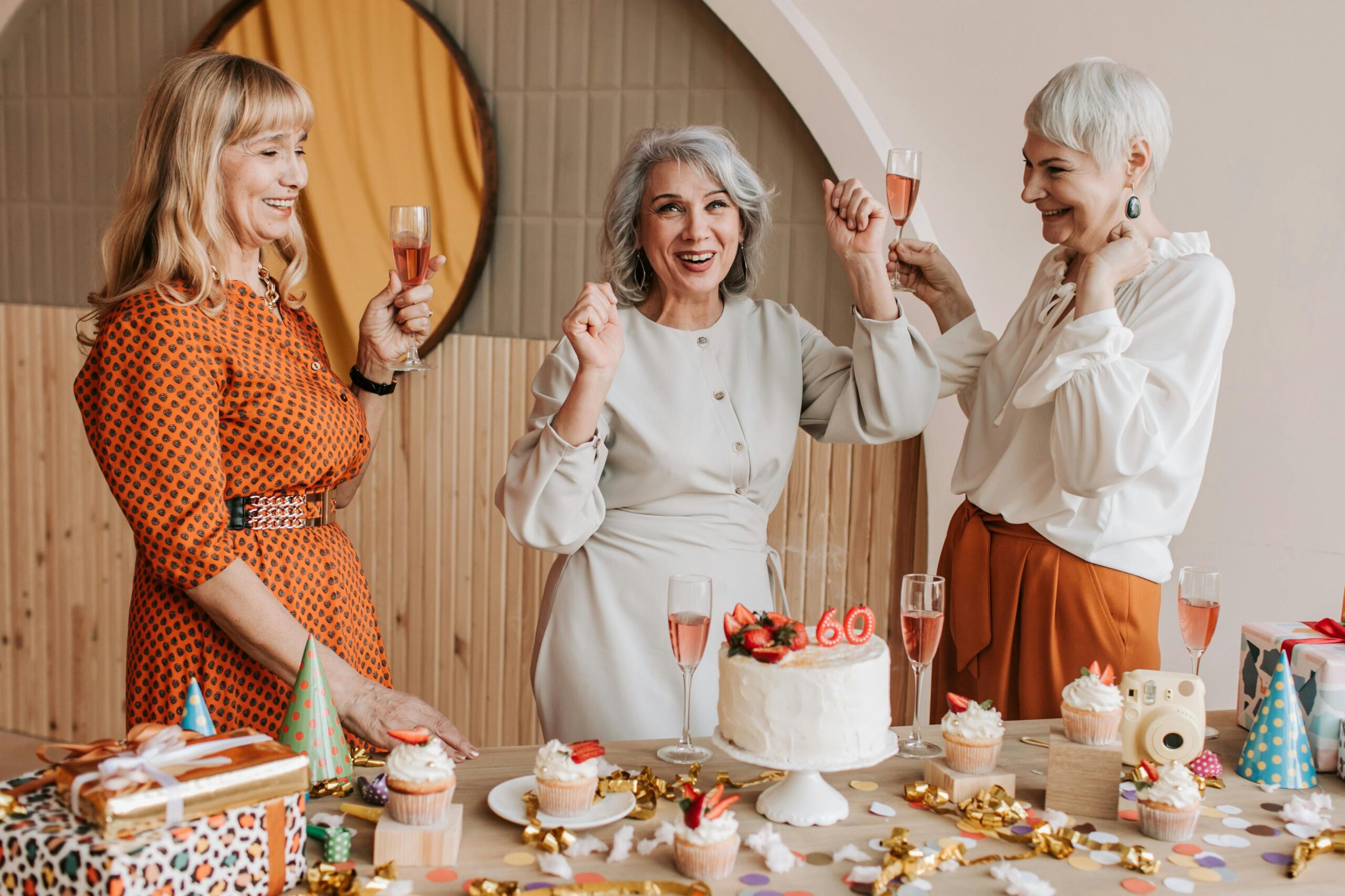Three women celebrating a 60th birthday with cake and candles
