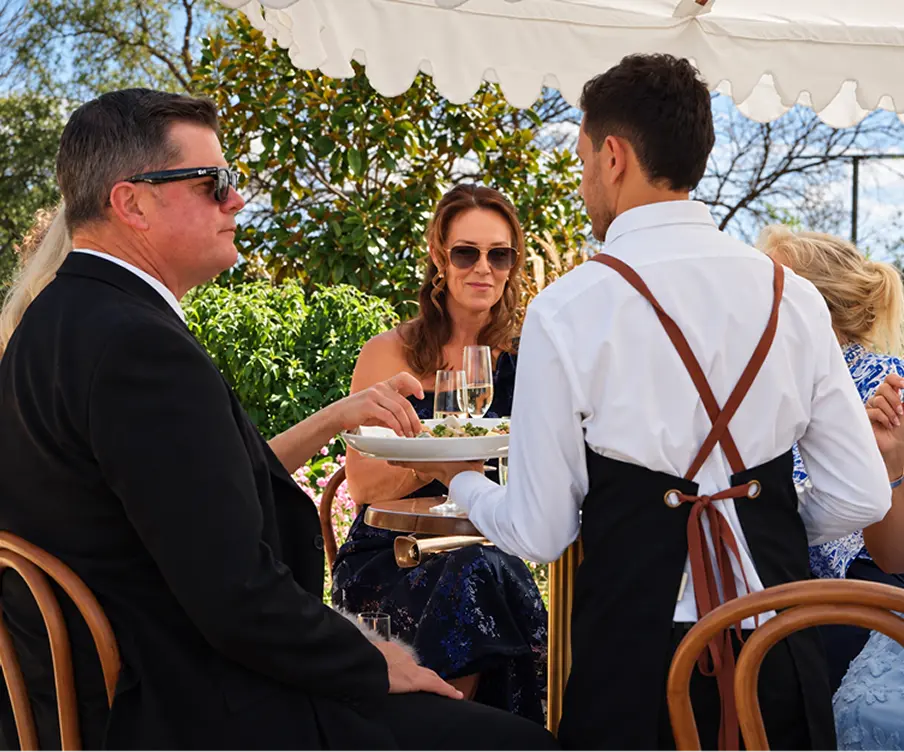 Waiter serving a plated course to seated guests at a Freshwater event