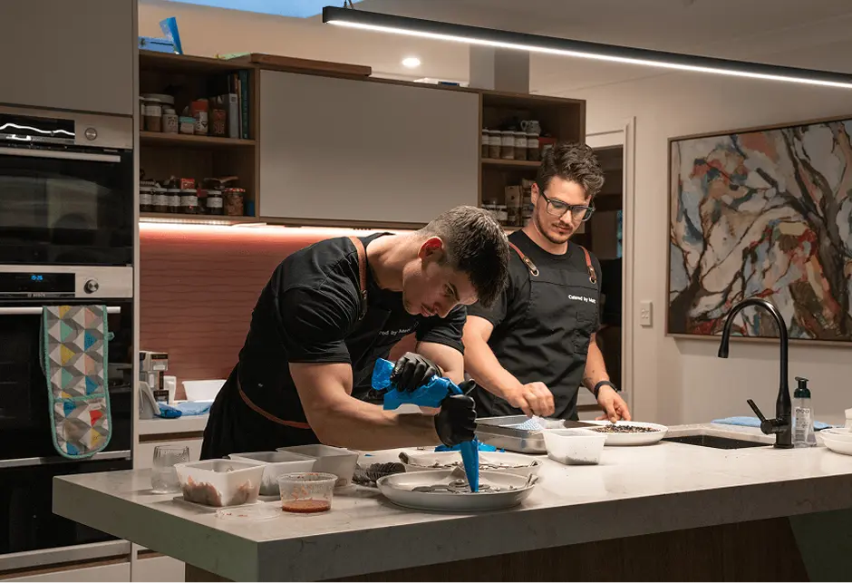 Chefs plating a course together in an Eastern Suburbs home kitchen