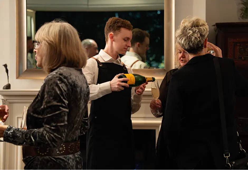 Waiter pouring sparkling wine for guests at a North Shore home celebration