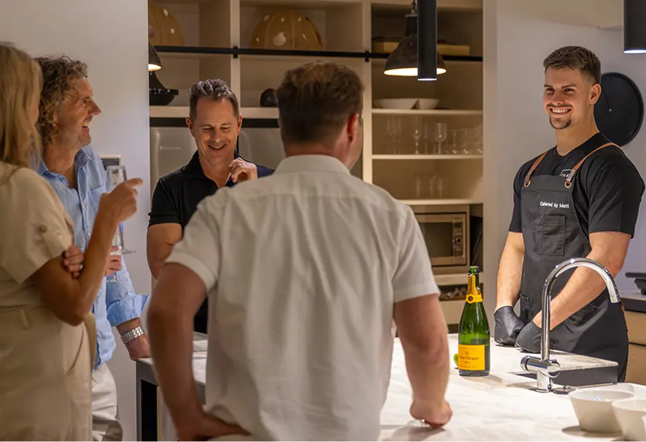 Chef Matt talking with guests across the kitchen bench at a Parramatta home party
