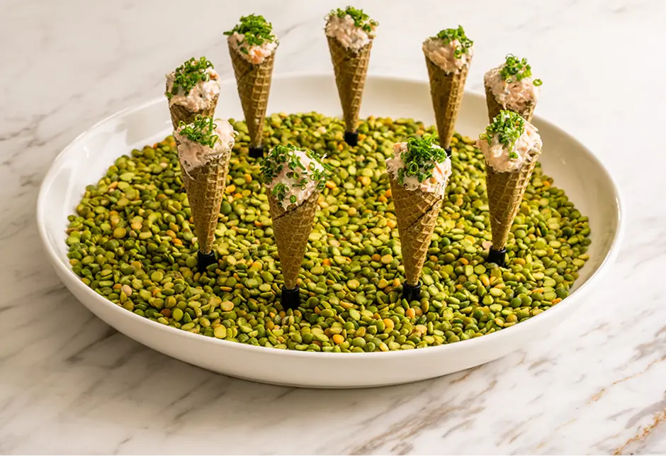 Crab remoulade cones standing in a bowl of green peas at a Castle Hill event