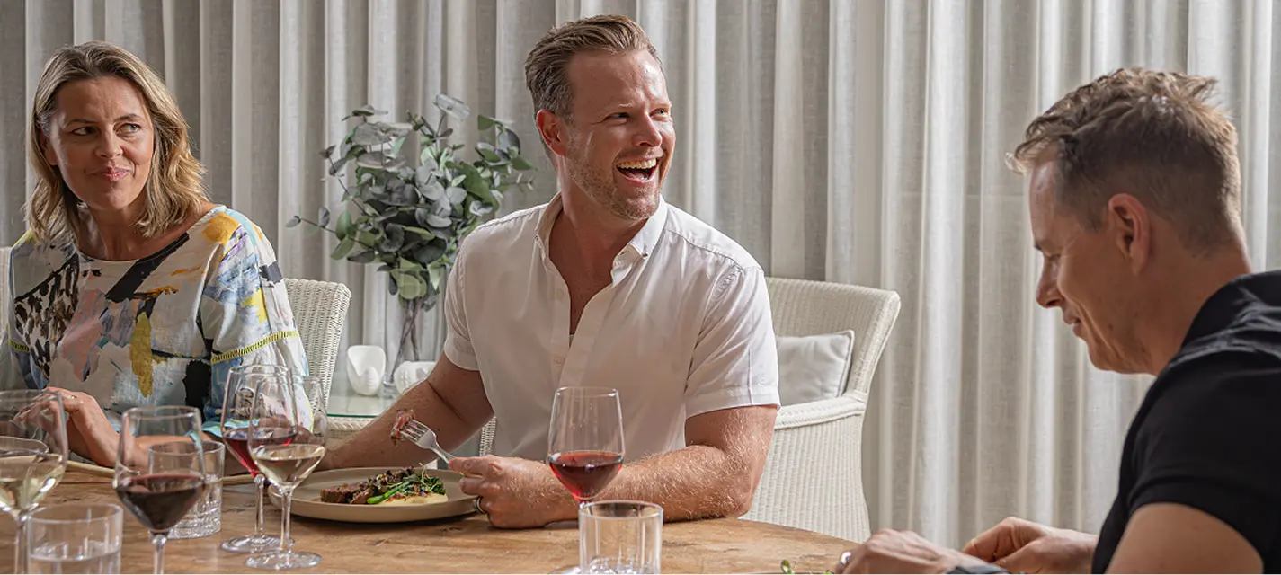 Guests laughing over red wine as a course is served at a Chatswood dinner party