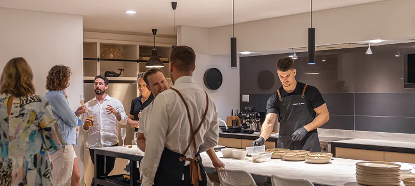 Guests mingling over drinks while a chef plates at a North Shore home party