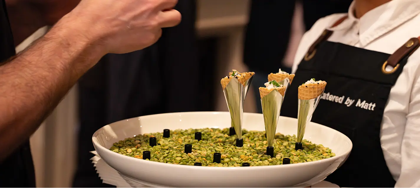 Waitstaff carrying cone canapés set in a bowl of peas at a Penrith event
