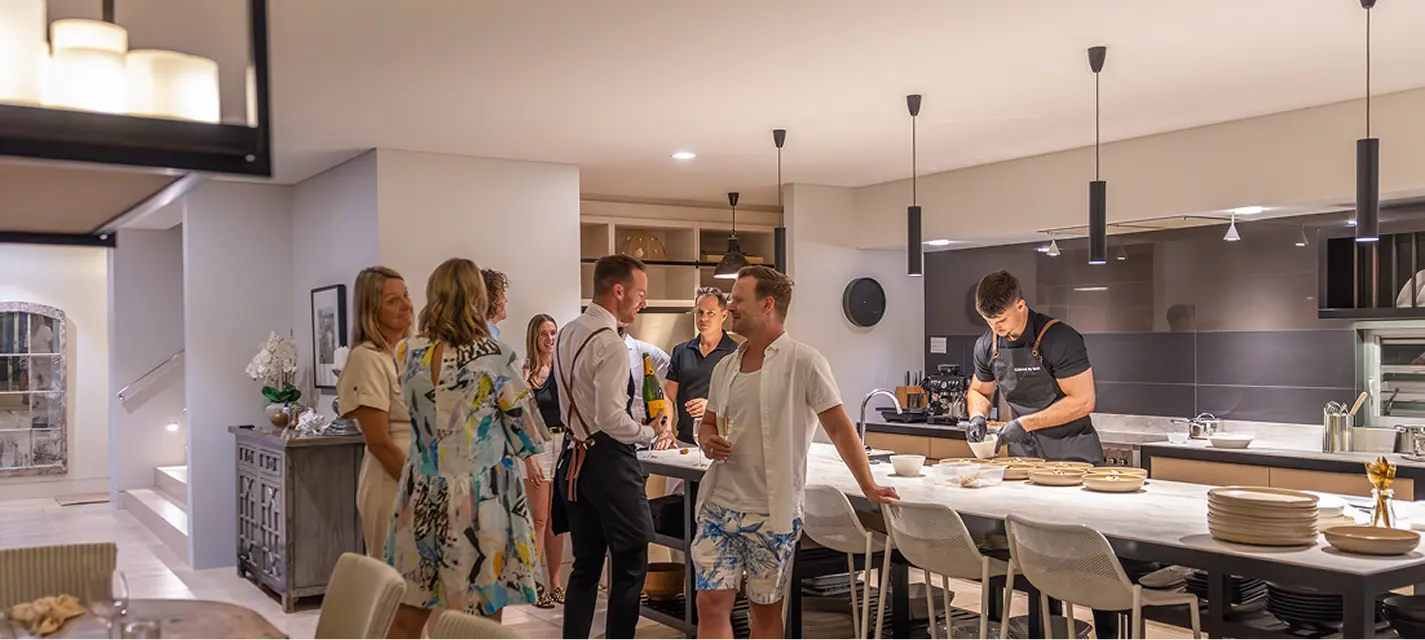 Guests mingling in the kitchen while a chef cooks at a Castle Hill home party