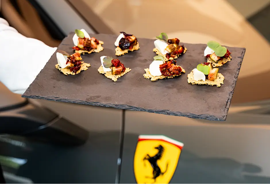 Slate board of canapés served beside a sports car at a Shire showroom event