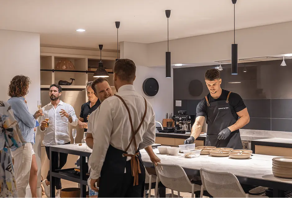 Guests mingling over drinks while chefs plate at an Eastern Suburbs home party