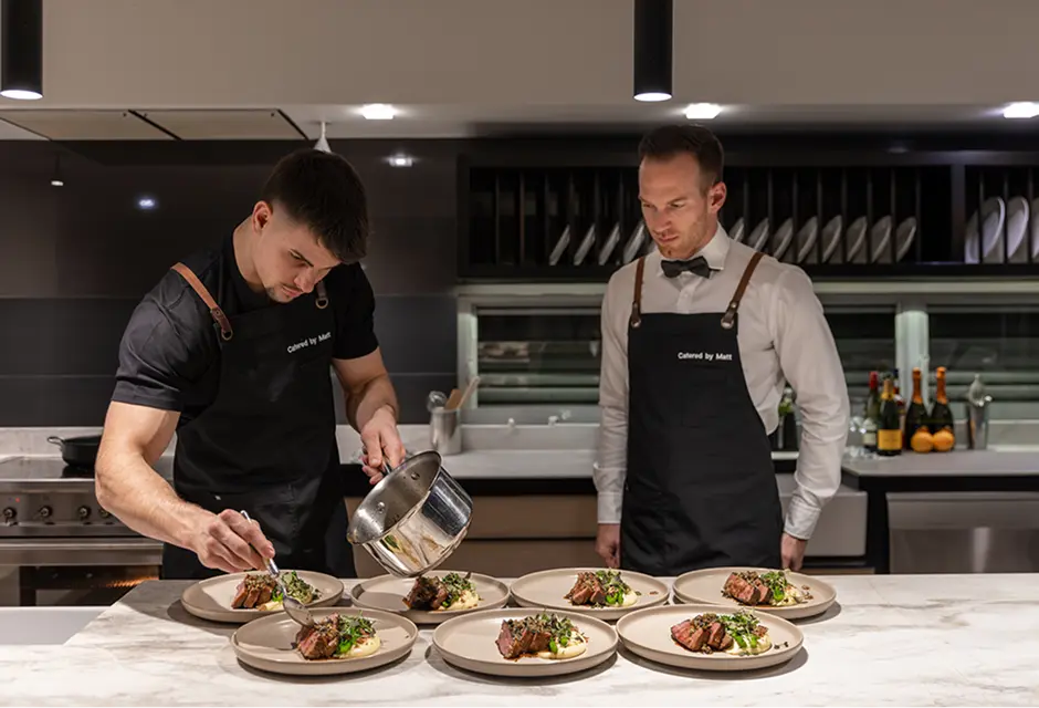 Chefs finishing plated courses side by side in a Castle Hill kitchen