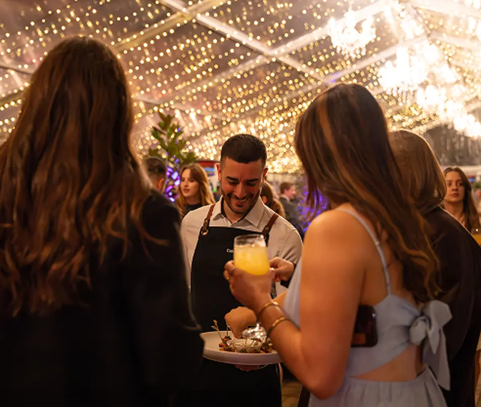Guests with cocktails taking canapés from waitstaff at a marquee party in Sydney