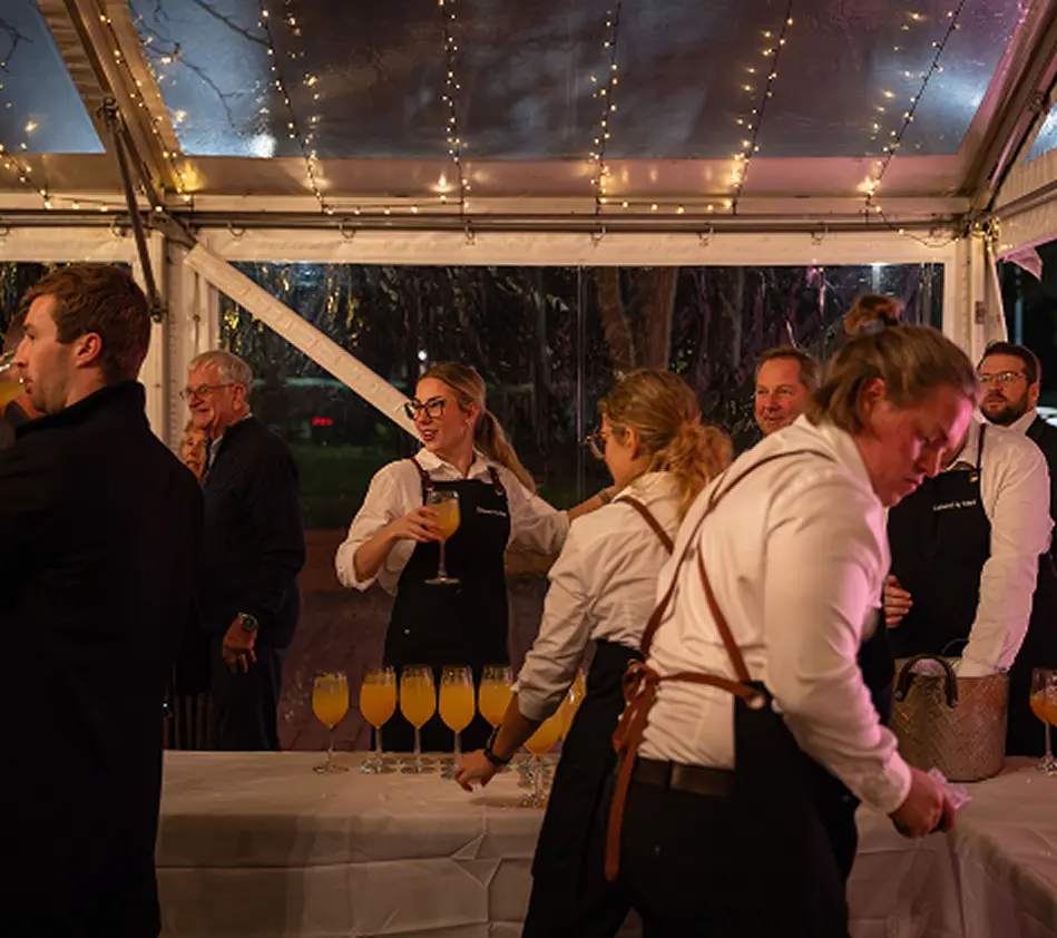 Catering staff serving drinks to guests under a marquee at an evening dinner party in Sydney