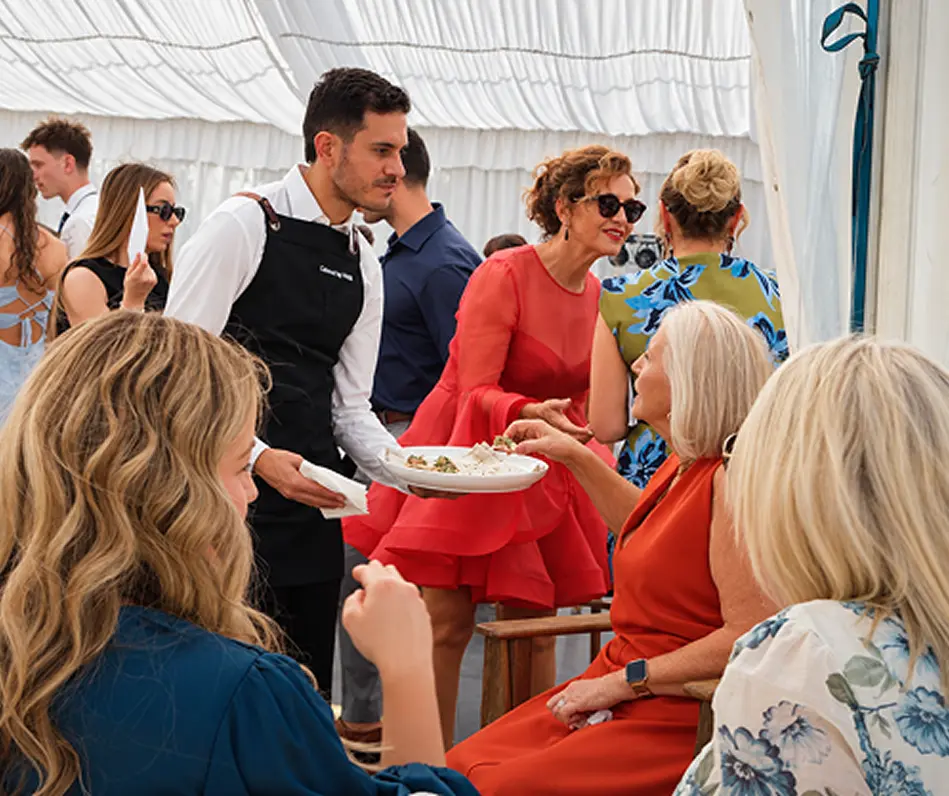 Waiter offering a plated dish to seated guests at a Bilgola event