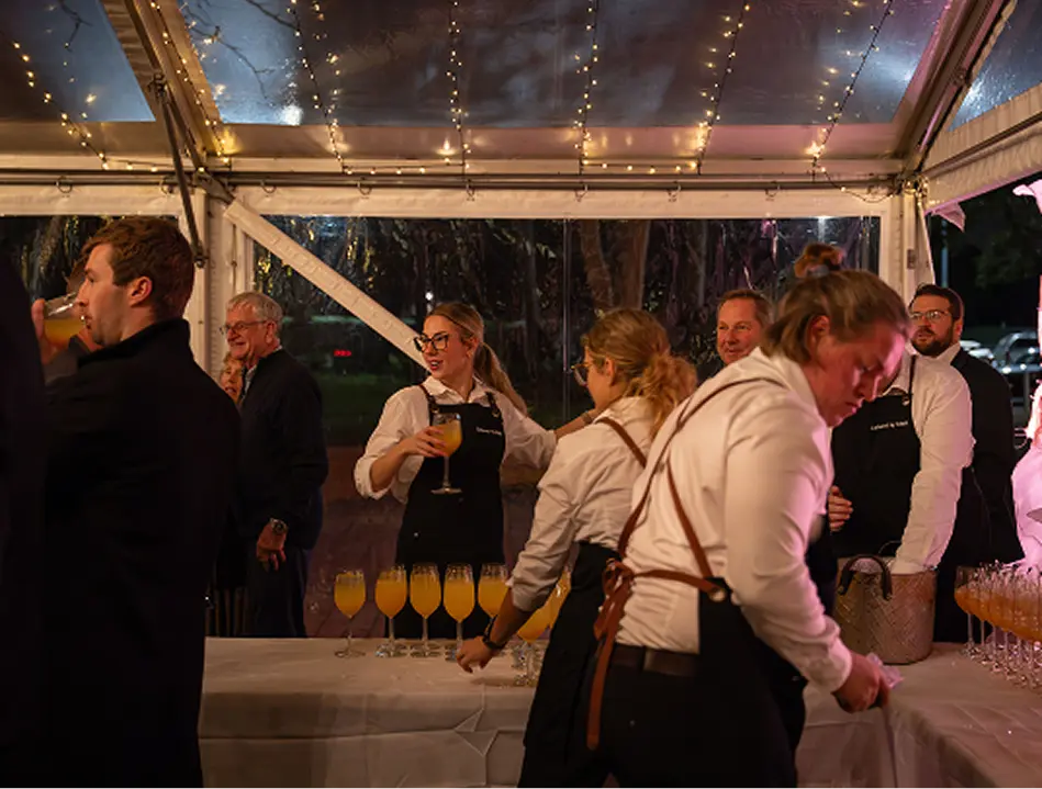 Staff running drinks service under a marquee at an Inner West event