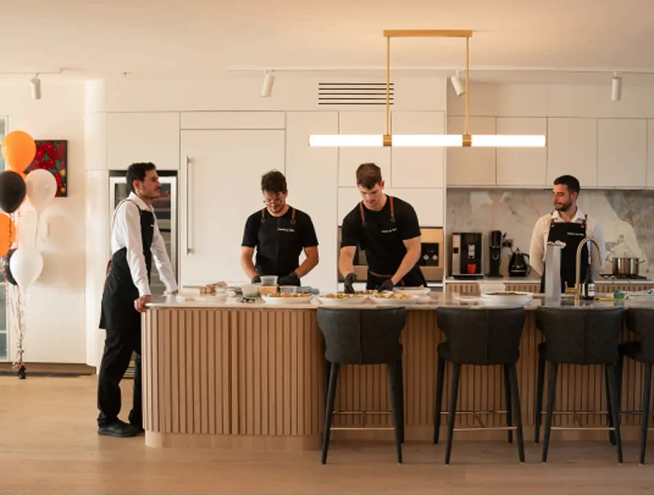 Catered by Matt team plating canapés in an open kitchen at a Sydney party, balloons in the background
