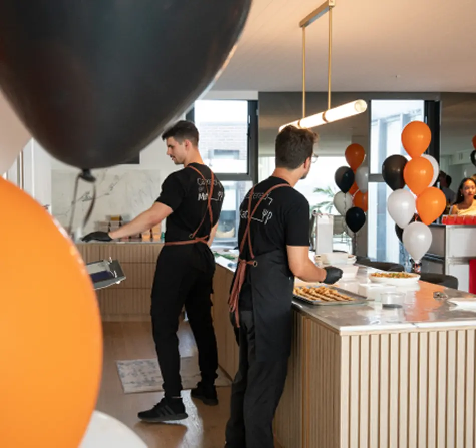 Chefs serving food from a kitchen bench surrounded by balloons at a Sydney birthday party