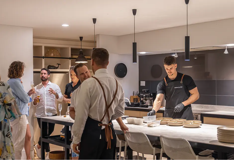 Guests mingling in the kitchen while chefs plate at an Inner West home party