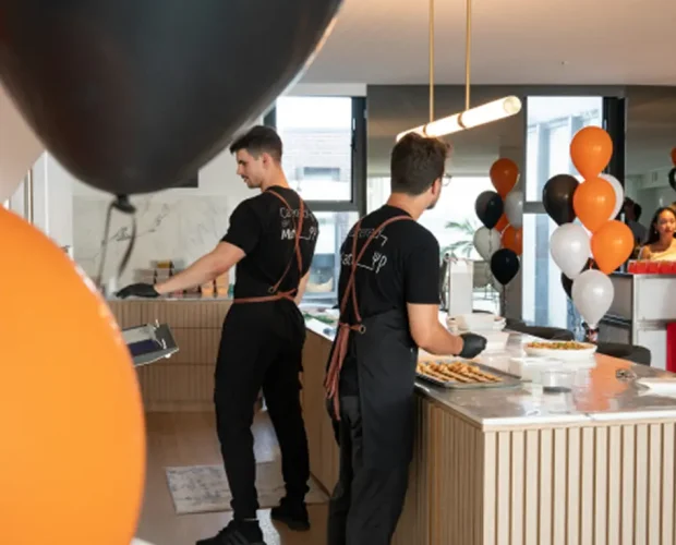 Chefs working the kitchen at a Sydney party with balloons behind them