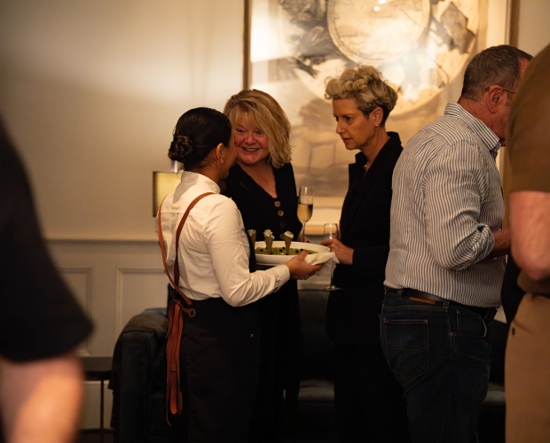 Guests smiling with waiter while enjoying canapés at Sydney event